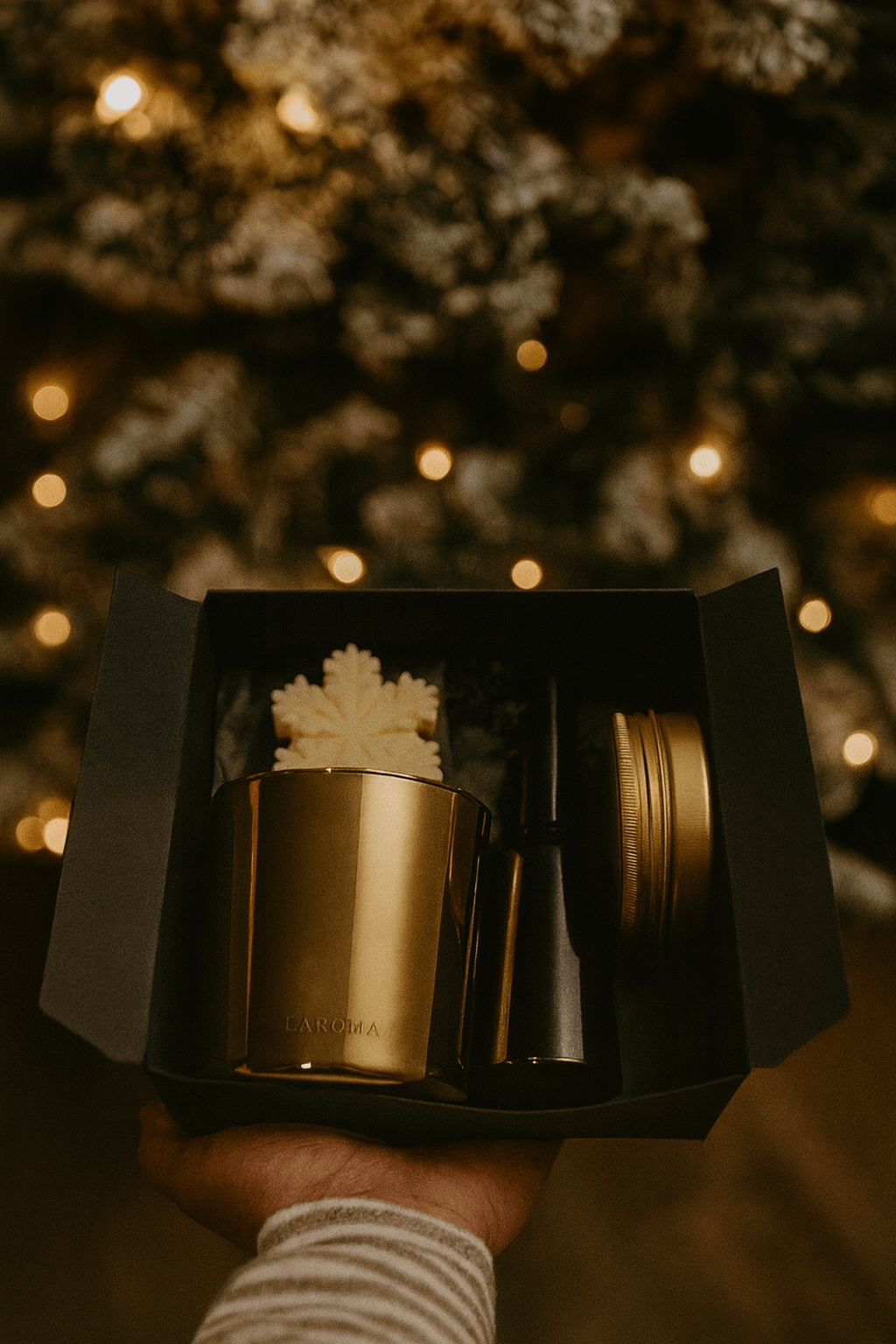 Gold mug with a maple leaf design in a black box against a blurred festive background