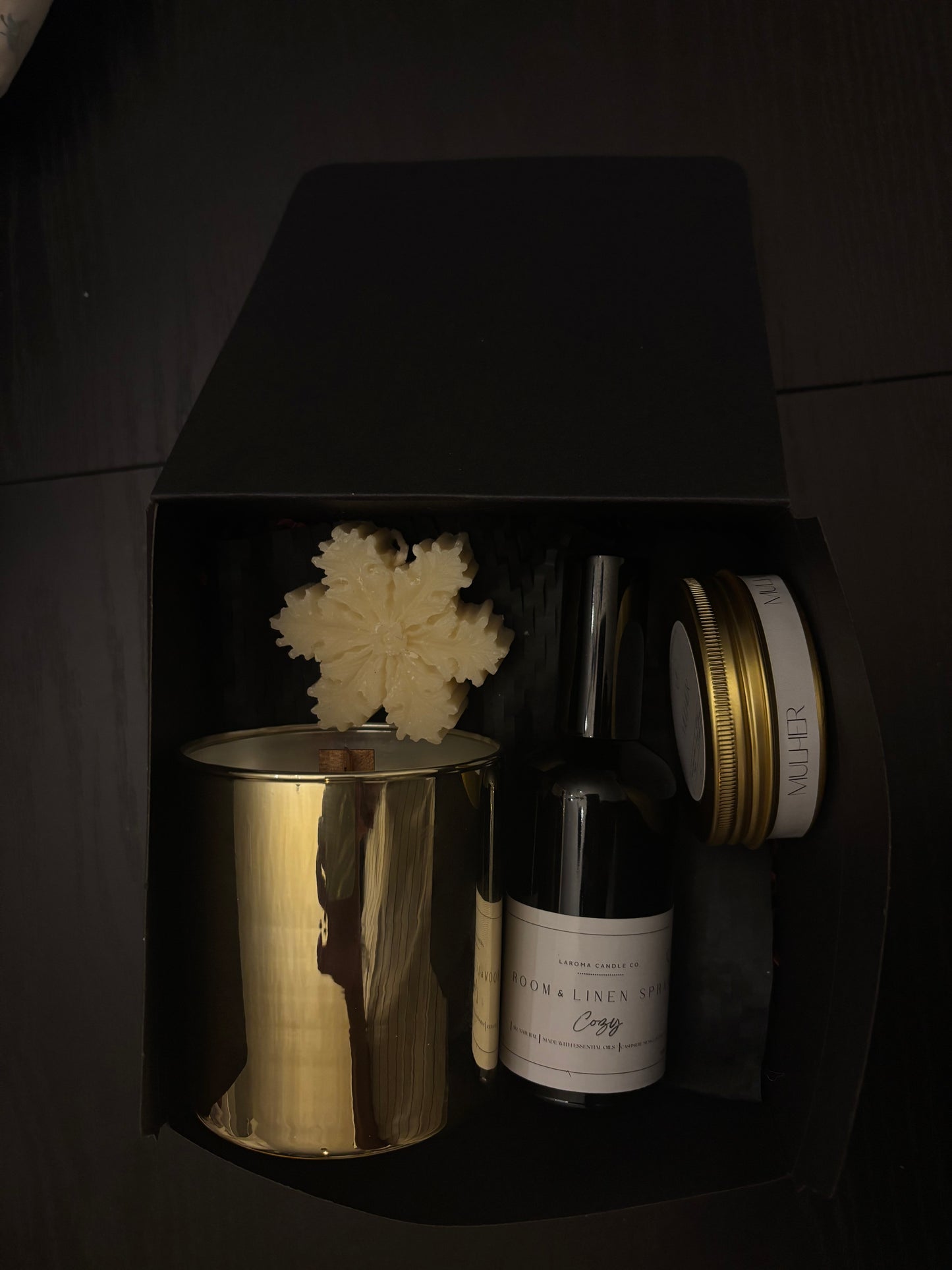 Bottle of a Room & Linen Spray with gold and white containers on a dark surface